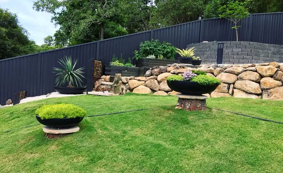 Dark Colorbond fence following a landscaped sloping garden