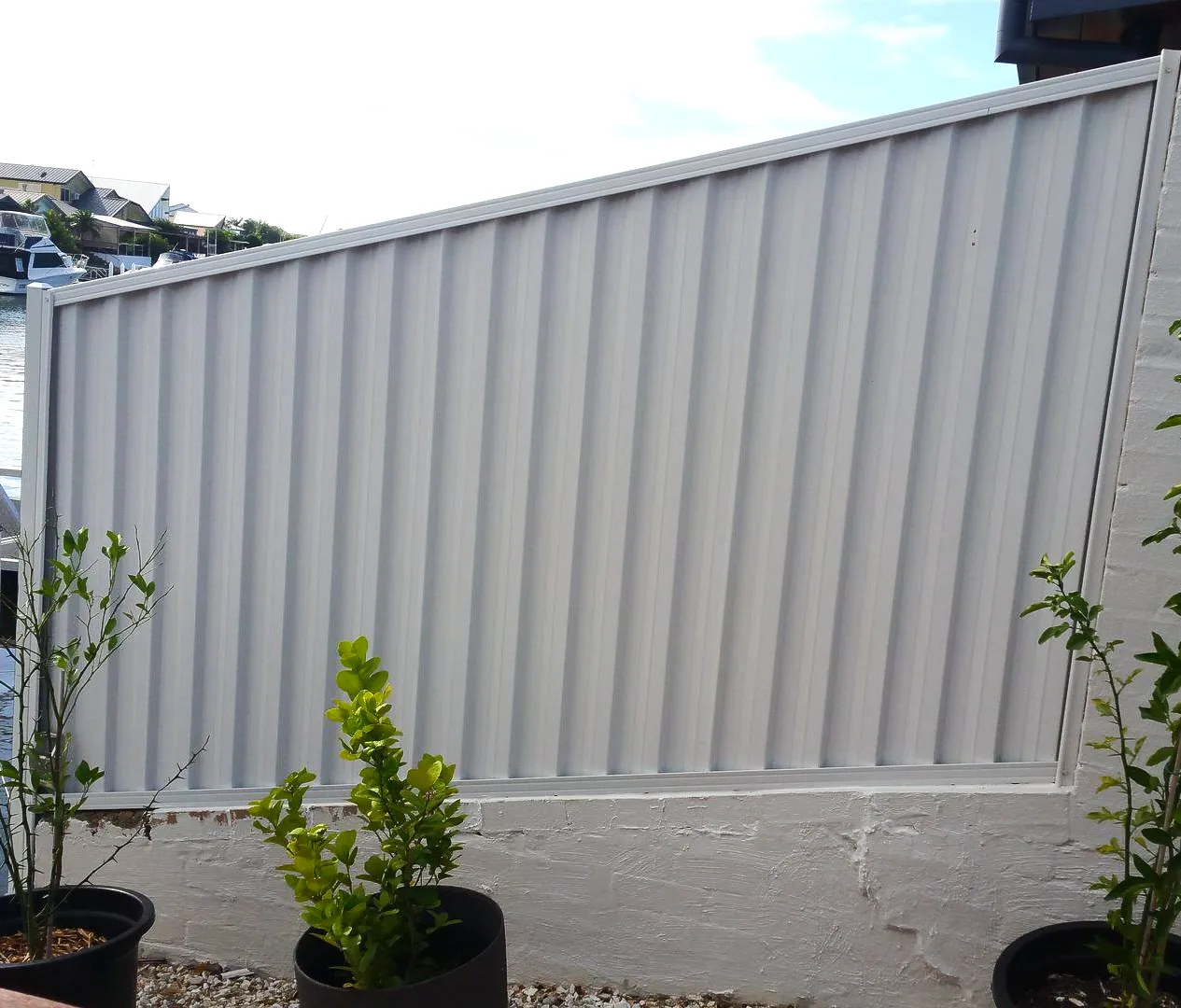 Light Colorbond fence installed above a rendered retaining edge