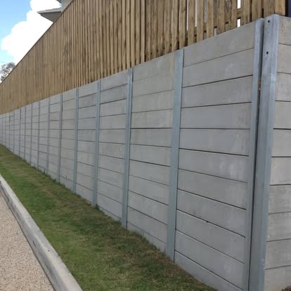 Long concrete sleeper retaining wall beneath a timber fence